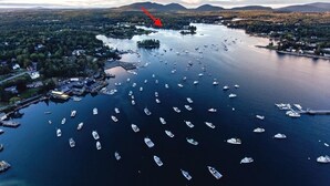 An aerial view of a lake with numerous boats, surrounded by forested areas and distant mountains. - Bass Harbor Oceanfront Chalet:  Peaceful, Private, Great On-The-Ocean View (Bass Harbor)