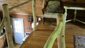 Un interior de madera con una escalera, una silla y una mesa.