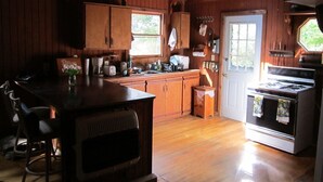 Una cocina rústica con gabinetes de madera, estufa y lavamanos.
