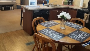 Cozinha compacta com área de refeições, incluindo lava-louças embutida, cafeteira e uma pequena ilha com pia.