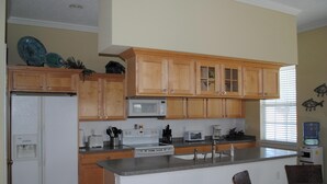 A large kitchen with wooden cabinets, a microwave, a stove, and a sink. - Casa Del Sol I - Large Single-Family Home With Private Pool  (South Padre Island)