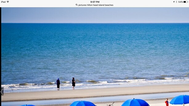 Une plage avec des parasols bleus, des chaises et des vélos.