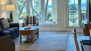 Un salon avec un canapé, un fauteuil, une table basse et un téléviseur posé sur une table en bois.