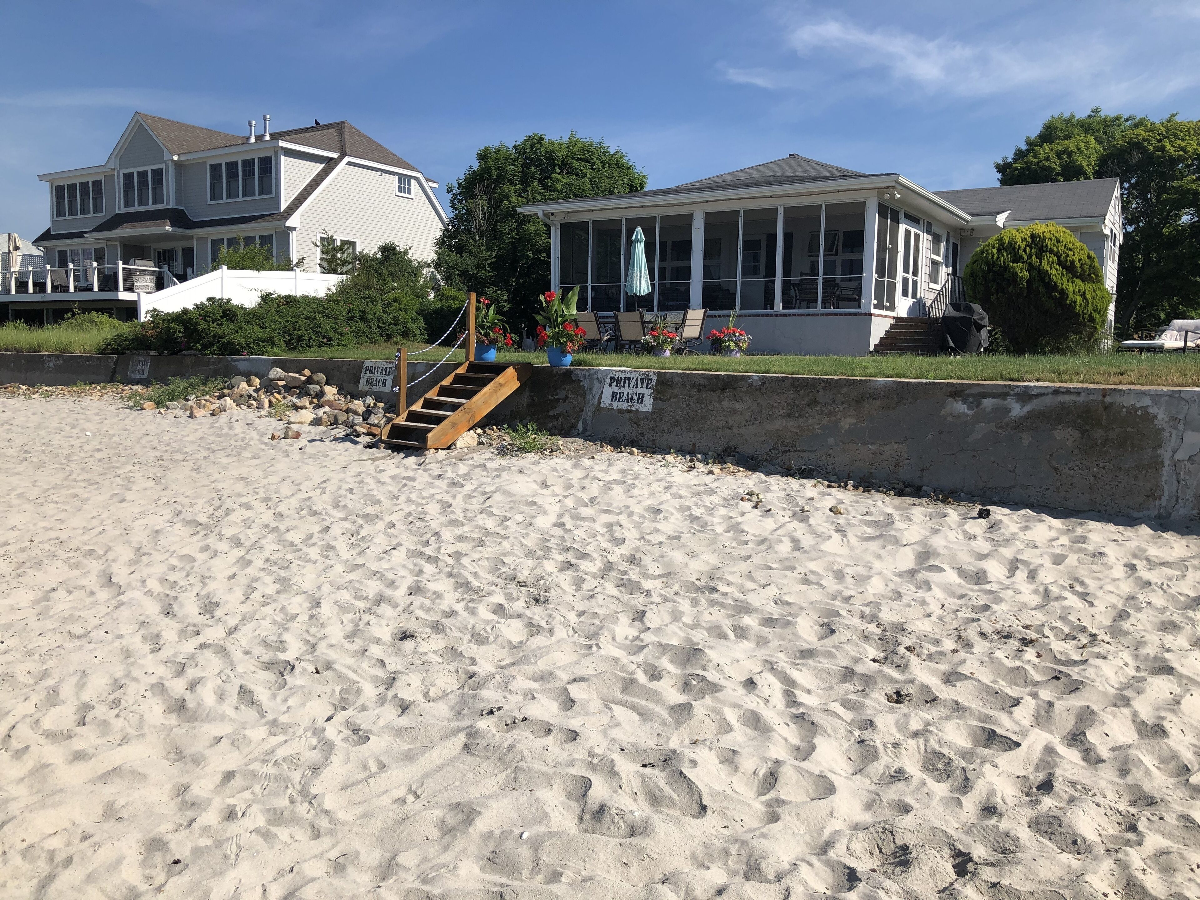 Une plage privée avec un escalier en bois menant à une maison.