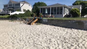 Une plage privée avec un escalier en bois menant à une maison.