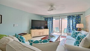 A living room with a flat-screen TV, beige sofa, and a coffee table. - SOUTH BEACH & PARK Just a Hop Skip & Jump • CORAL COTTAGE • Fun Seaside Vero  (Vero Beach)