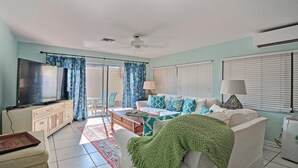 A living room with a TV, sofa, and a dining area with chairs. - SOUTH BEACH & PARK Just a Hop Skip & Jump • CORAL COTTAGE • Fun Seaside Vero  (Vero Beach)