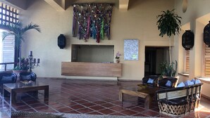 Eine großzügige Lobby mit Holztresen, einer Sitzecke und einer Wand, die mit bunten Fransen verziert ist.