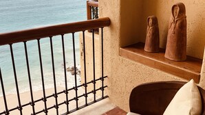 Ein Balkon mit Meerblick, ein Stuhl mit Kissen und zwei wandförmige Sonnendekorationen.