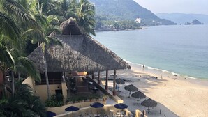 Ein Resort-Pool mit Liegestühlen und Sonnenschirmen, ein Strand und Palmen.
