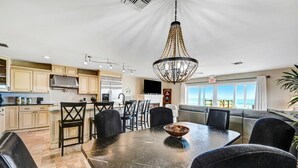 A modern kitchen with beige cabinets, a black marble countertop, and a chandelier. - Direct Oceanfront Heavenly Retreat (Melbourne Beach)