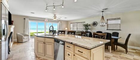 A spacious kitchen with a large island, modern appliances, and a view to the outdoors.