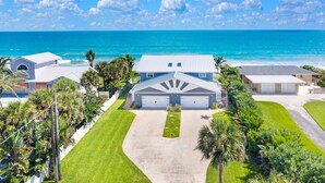A residential area with a large house featuring a garage, a driveway, and a well-maintained lawn. - Direct Oceanfront Heavenly Retreat (Melbourne Beach)