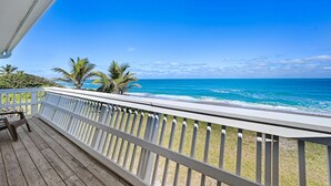 A wooden deck with a white railing overlooking a beach with palm trees and the ocean. - Direct Oceanfront Heavenly Retreat (Melbourne Beach)