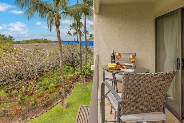 A balcony with a table, chairs, and a bottle of wine.