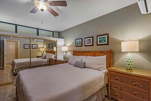 A hotel room with a large bed, two bedside tables, a ceiling fan, and framed pictures on the wall. - Quiet Kihei 4th Floor Condo Hawaiian Decor Cal King Lanai Ocean Views Pool (Kihei)