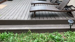 Ett trädäck med utemöbler, inklusive solstolar och ett bord med ett parasoll.