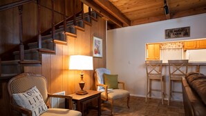 Ein gemütliches Blockhaus mit Holzwänden, einer Treppe, einem Essbereich und einem Wohnzimmer mit Sofa und Sesseln.