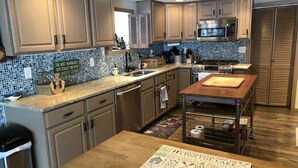 A kitchen with wooden cabinets, a stainless steel sink, a microwave, and a wooden island with a cutting board.