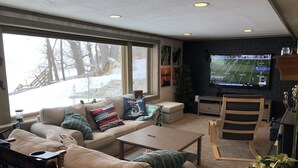 A cozy living room with a large window, a television, and a comfortable seating area.