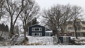 A two-story house with a snow-covered yard and a staircase leading to the entrance.