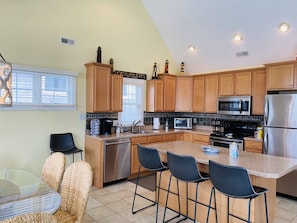 A modern kitchen with wooden cabinets, stainless steel appliances, and a central island with bar stools.