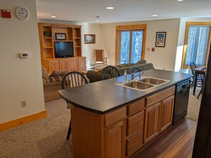 Una cocina moderna con una isla central, armarios de madera y lavavajillas integrado.