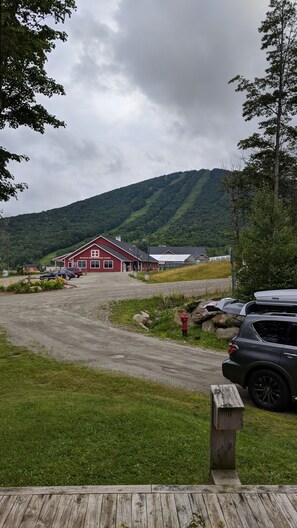 Un edificio rojo con el rótulo "Mountain King Adventure Center", con un camino de grava que conduce al edificio, rodeado de vegetación y colinas.