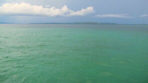 Blick auf ein ruhiges Meer mit einer fernen Küste und einem bedeckten Himmel.