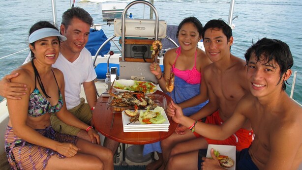 Eine Gruppe von Menschen auf einem Boot, an einem Tisch gedeckt für eine Mahlzeit.