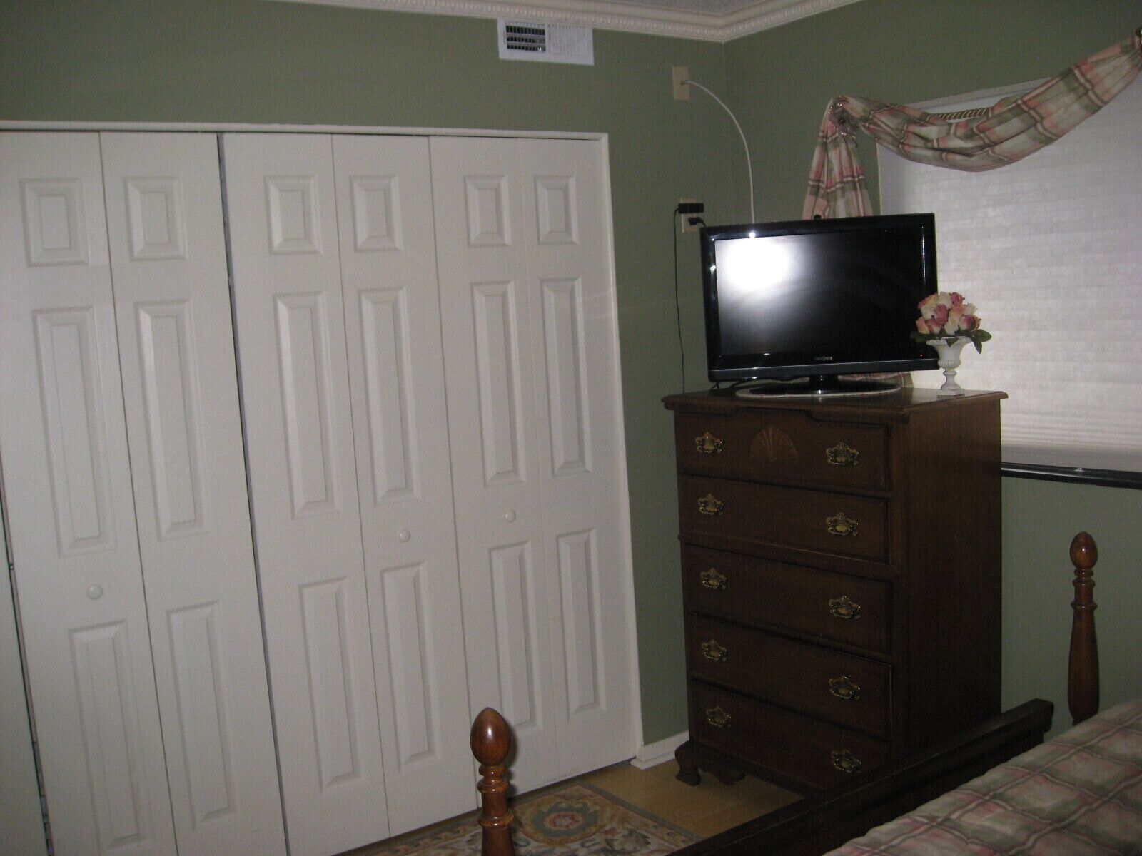 Un dormitorio con una cama, un aparador con un televisor encima y un armario.