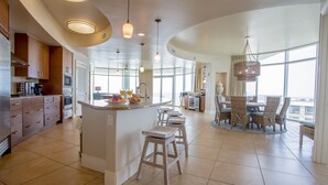 A spacious kitchen with a central island, bar stools, and a dining area with wicker chairs. - 4 bedroom D Tower!! Turquoise Complex (Orange Beach)