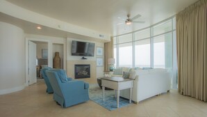 A spacious living room with a white sofa, blue armchairs, a flat-screen TV, and a fireplace. - 4 bedroom D Tower!! Turquoise Complex (Orange Beach)