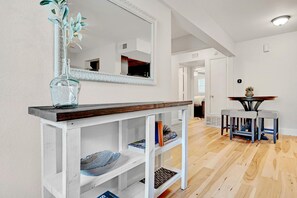 A modern living room with a white console table, a large mirror, and a wooden floor. - Renovated 3BA/2BD Condo 2 Miles from Downtown (Austin)