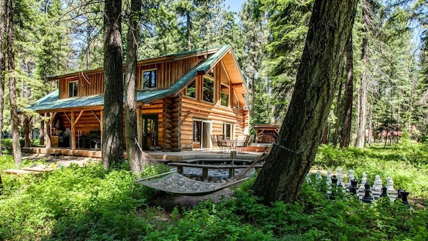 Eine Blockhütte mit einem grünen Dach, umgeben von dichtem Wald.