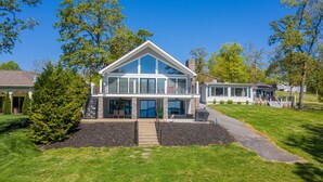 Une maison moderne à deux étages, dotée d’une grande véranda à l’avant, d’un patio couvert et de fondations en pierre.