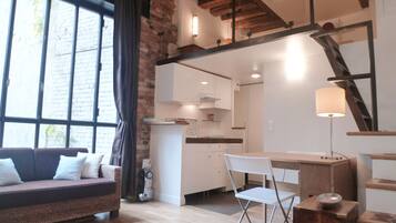 Un soggiorno moderno con un divano, un'area pranzo con tavolo e sedie e una cucina sullo sfondo.