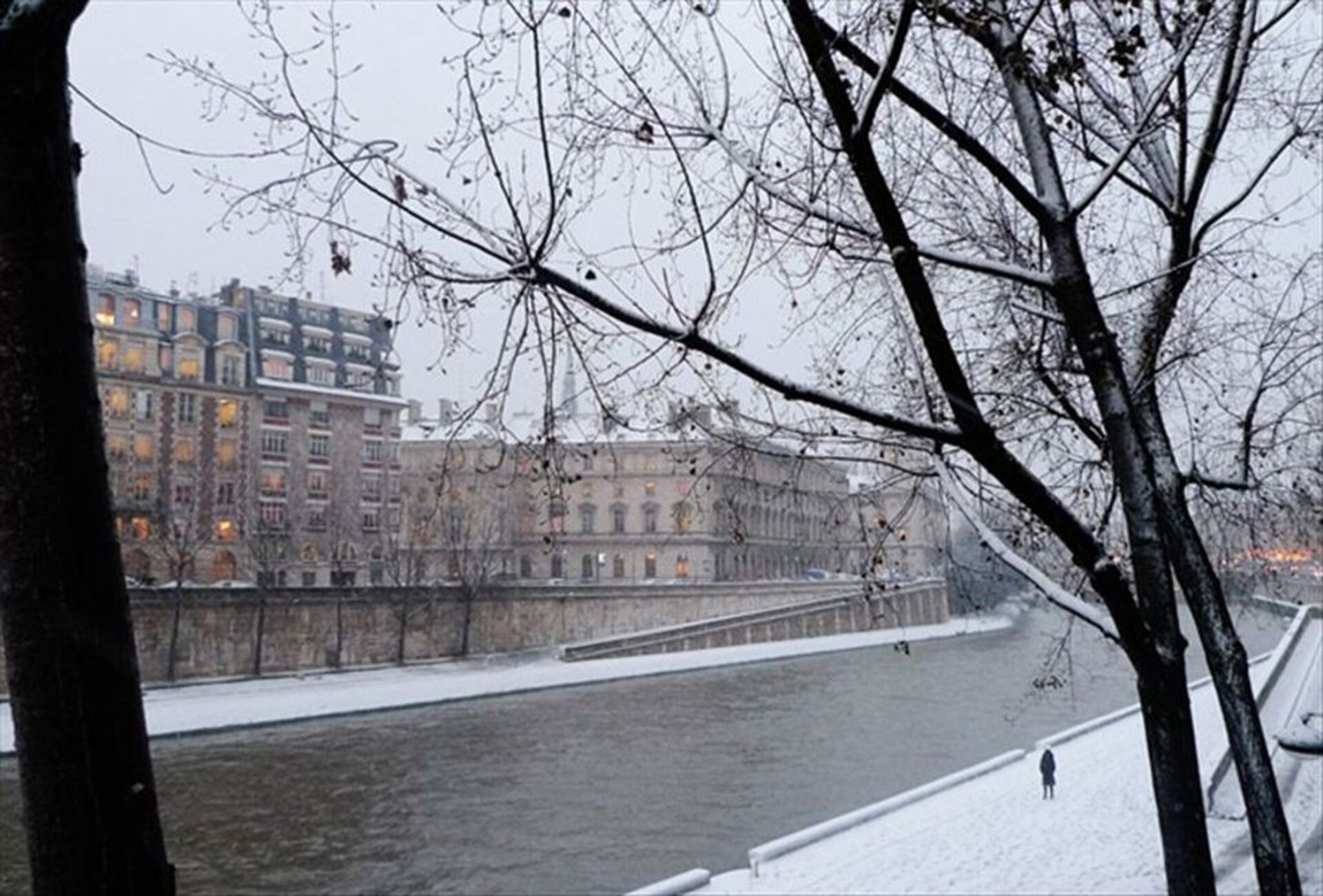 A snow-covered river with buildings in the background.