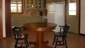 Une cuisine avec une table ronde en bois et deux chaises, un réfrigérateur et des placards.