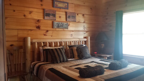 Ein Schlafzimmer einer Holzhütte mit einem Bett, Kissen und einer Wand mit gerahmten Bildern.