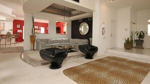 A modern living room with a gray sectional sofa, black armchairs, a glass coffee table, and a leopard print rug. - Pool Compareable to Mirage, Palapa, 82 in Hd TV, Minutes from Strip (Las Vegas)