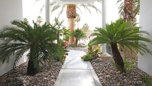 A pathway flanked by palm trees and pebbles, leading to a building with columns. - Pool Compareable to Mirage, Palapa, 82 in Hd TV, Minutes from Strip (Las Vegas)