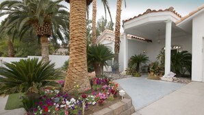 A covered patio area with a concrete floor, surrounded by a variety of plants and flowers. - Pool Compareable to Mirage, Palapa, 82 in Hd TV, Minutes from Strip (Las Vegas)