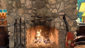 A stone fireplace with a fire, surrounded by decorative items and a rustic interior.
