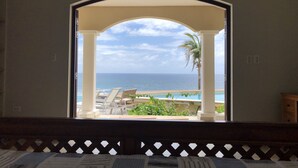 A room with a view of the ocean through an arched doorway, a pool, and lounge chairs. - Luxury Villa w Spectacular Ocean Views, private pool/Hottub, Walk to Beach (Upper Prince's Quarter)