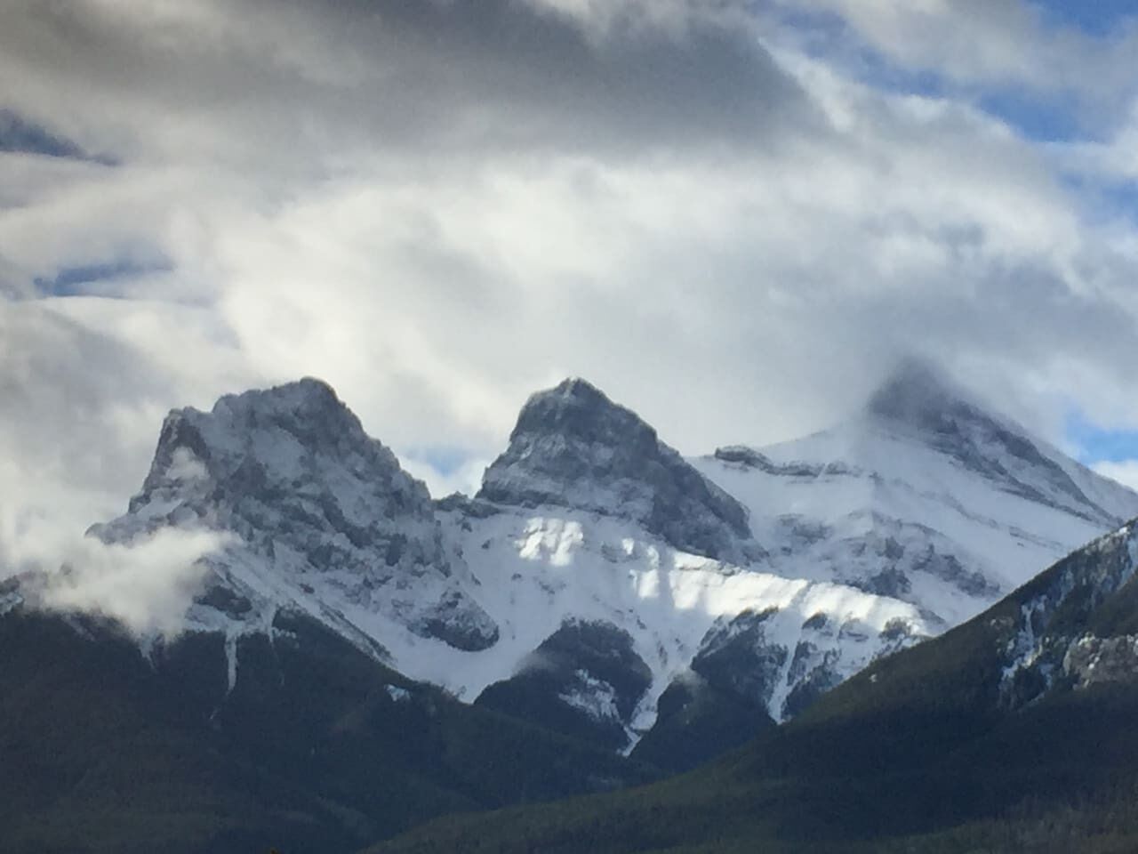 Un paisaje montañoso con picos nevados y un valle.