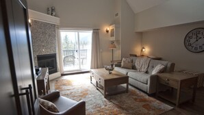 A spacious living room with a fireplace, a sofa, a coffee table, and a clock on the wall.