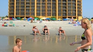 A high-rise hotel with multiple balconies, located near a beach with umbrellas and beach chairs. - Spectacular VIP Corner Oceanfront @ Anderson Ocean, Wrap-Around Balcony 2B/2Ba (Myrtle Beach)