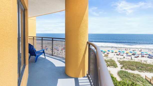 A balcony with a view of the beach, a chair, and a large pillar. - Spectacular VIP Corner Oceanfront @ Anderson Ocean, Wrap-Around Balcony 2B/2Ba (Myrtle Beach)