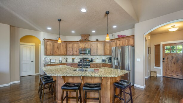 A spacious kitchen with wooden cabinets, a central island with stools, and modern appliances.